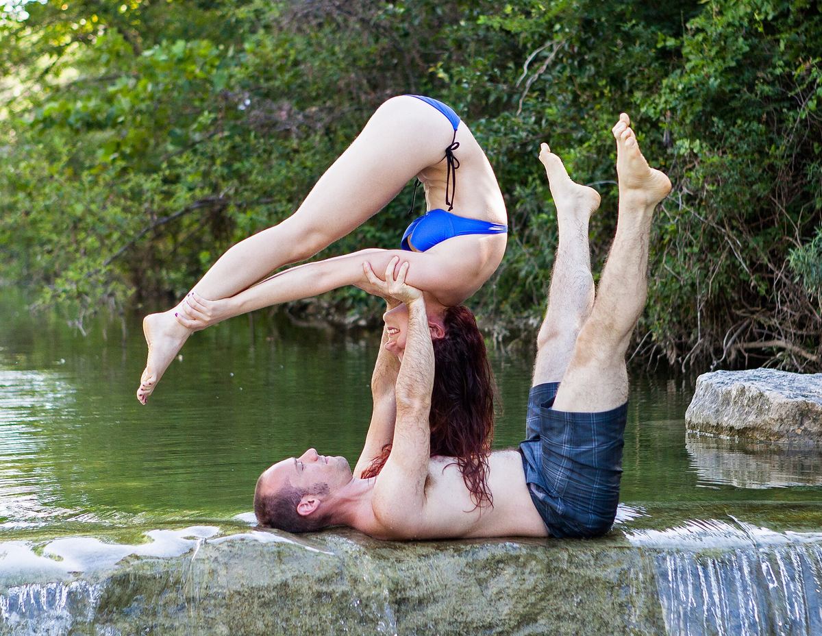 Zwei Personen in einer Acro-Yoga-Figur, eine trägt die andere